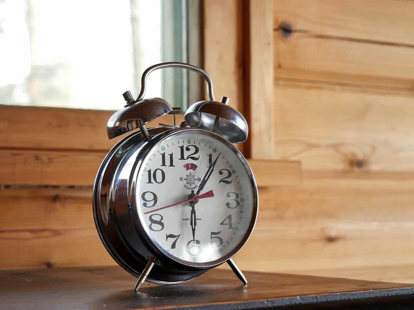 A classic alarm clock on a wooden windowsill
