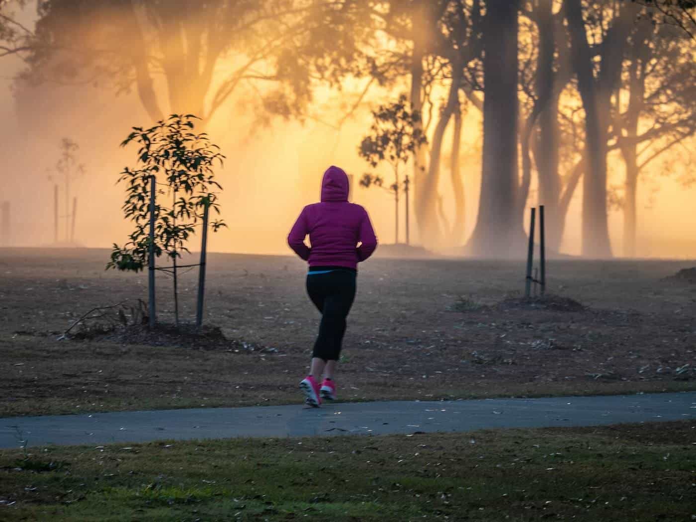 A person jogging through a park in morning mist