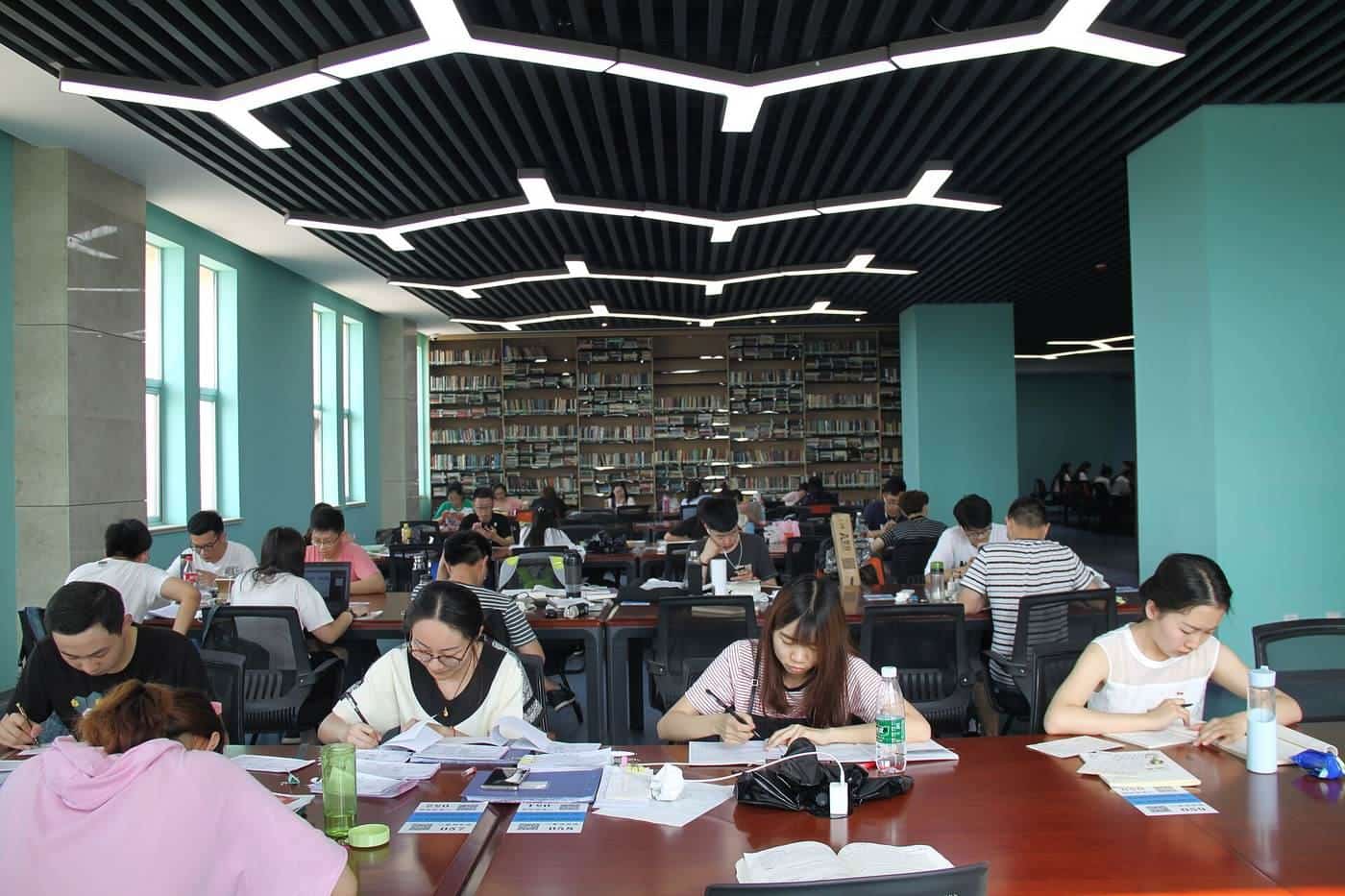 Students studying at long desks in a busy library