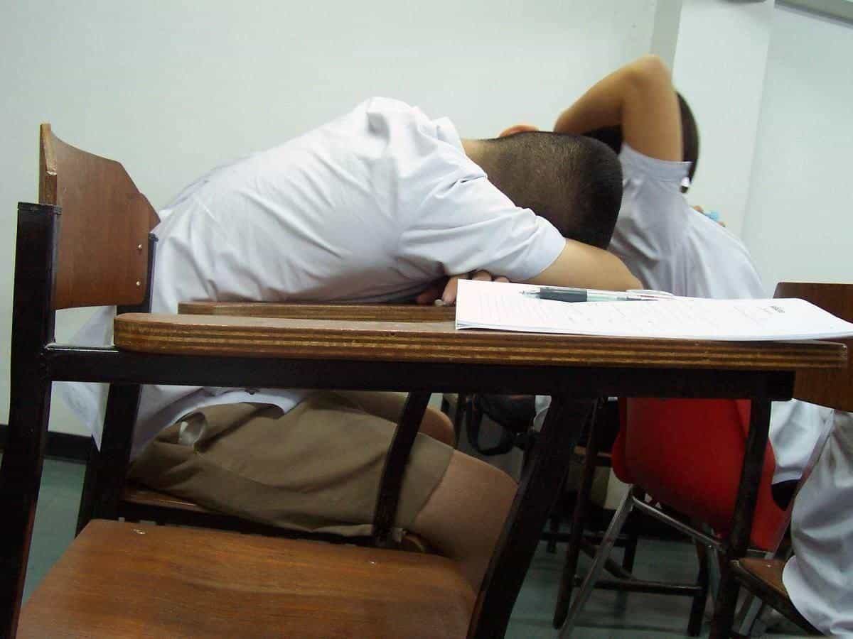 A student asleep at a desk with papers