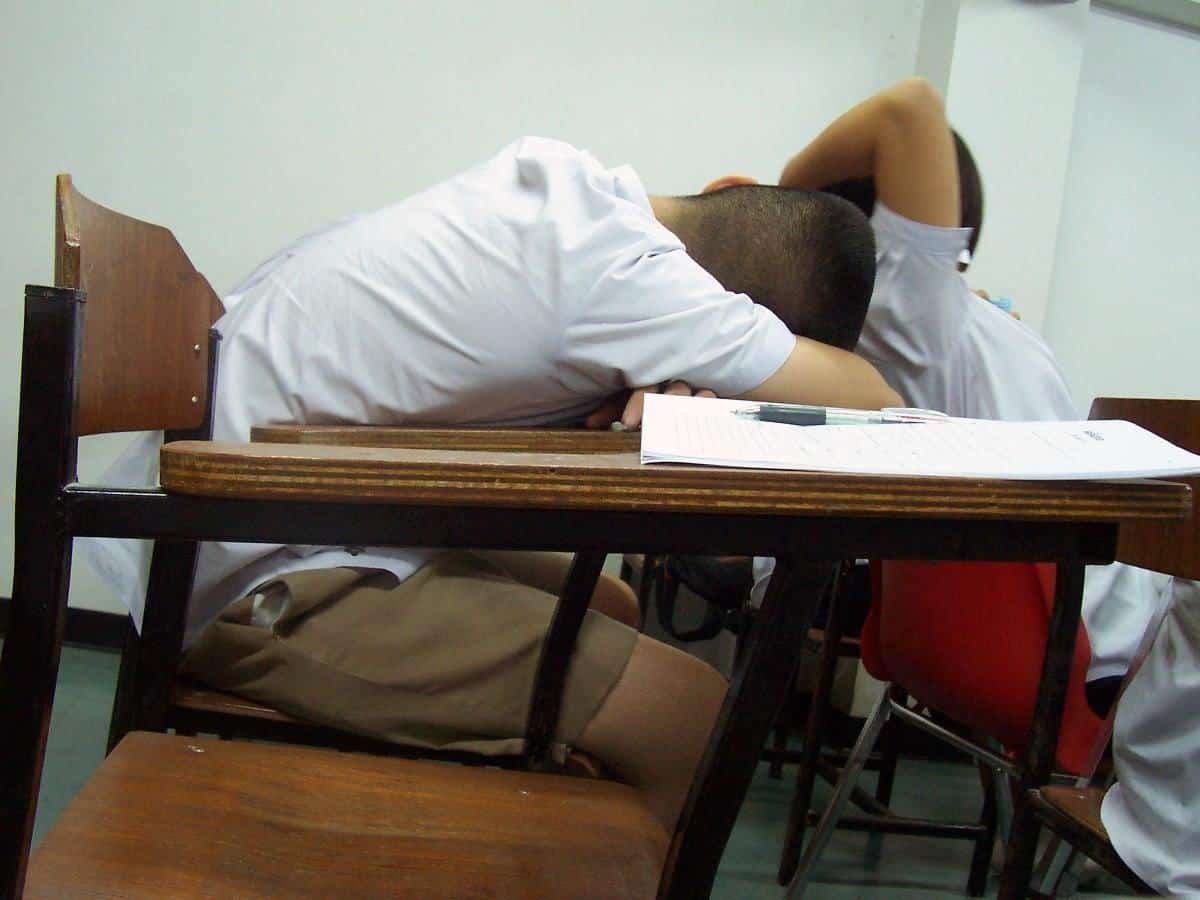 A student asleep at a desk with papers